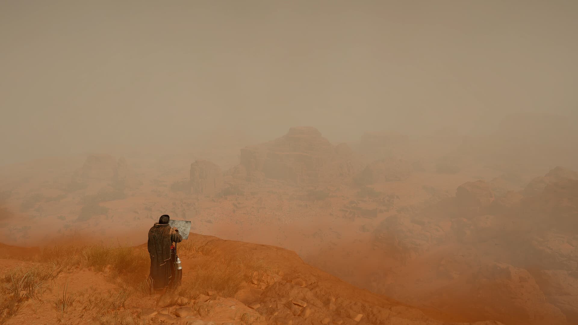A lone figure looks across a dusty orange desert towards distant rock formations.