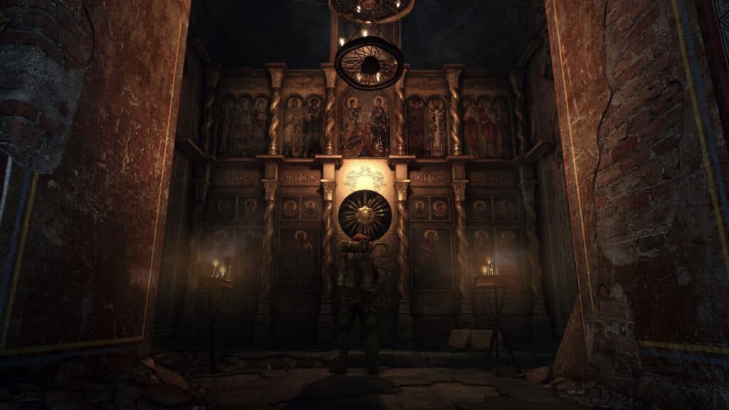 Warm light illuminates a shrine-like wall inside a dark underground room.