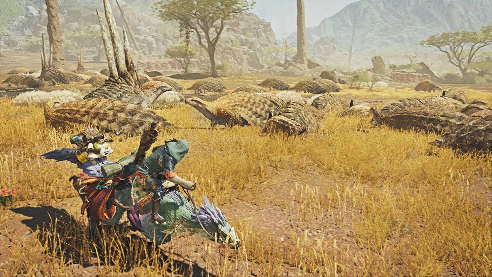 A mounted hunter crosses golden grass beside a herd of large creatures.